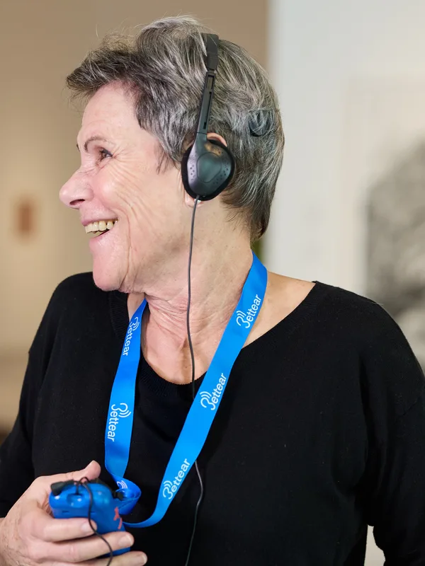 A visitor smiling as she listens on headphones connected to an RTX receiver