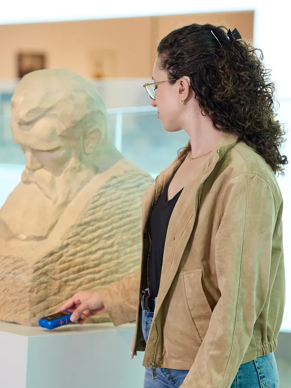 A visitor holding an RTX receiver beside a sculpture