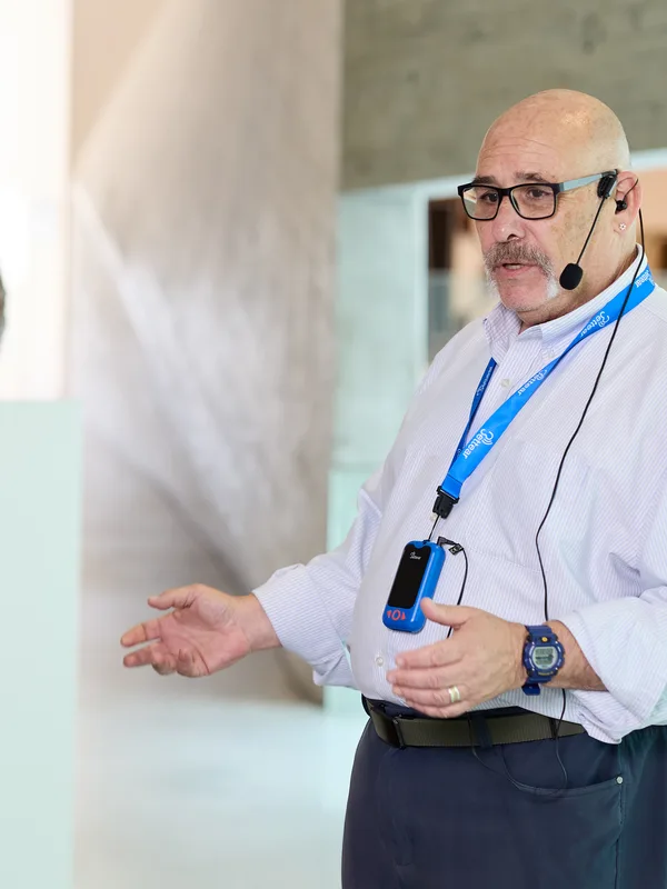 A museum guide speaking into a headset microphone to his group