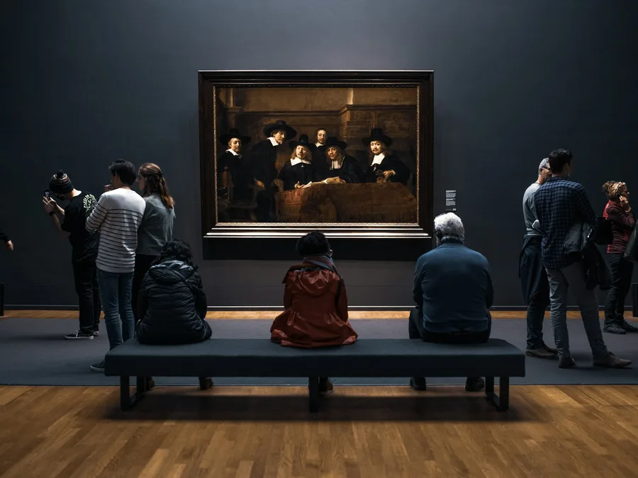 Visitors in a museum gallery in front of a large painting