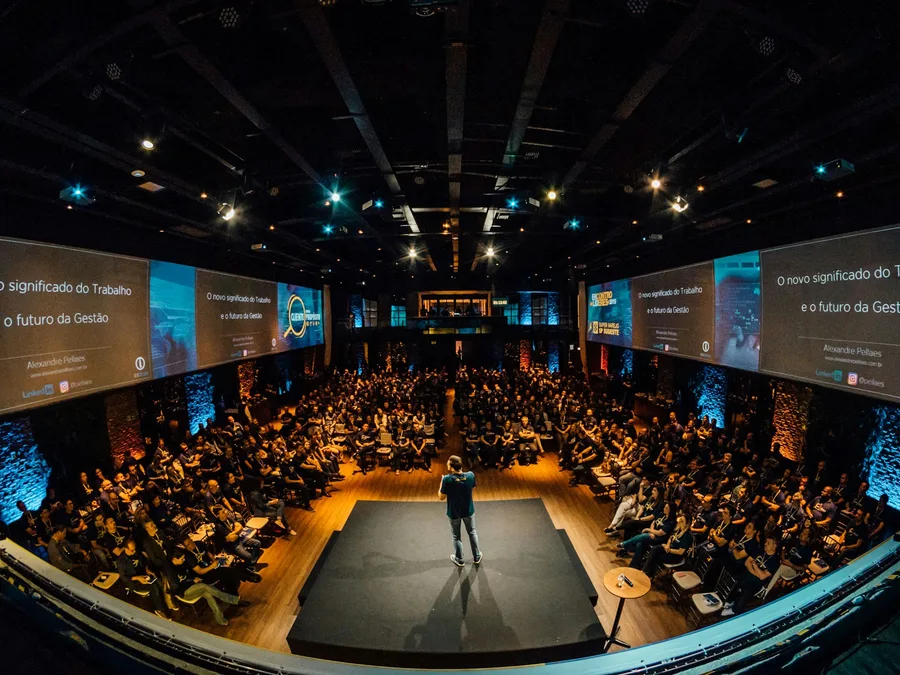 A speaker on stage in front of a large conference audience