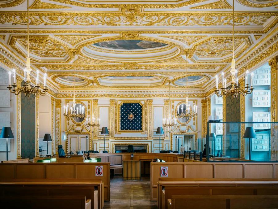 An ornate courtroom with gilded walls and chandeliers