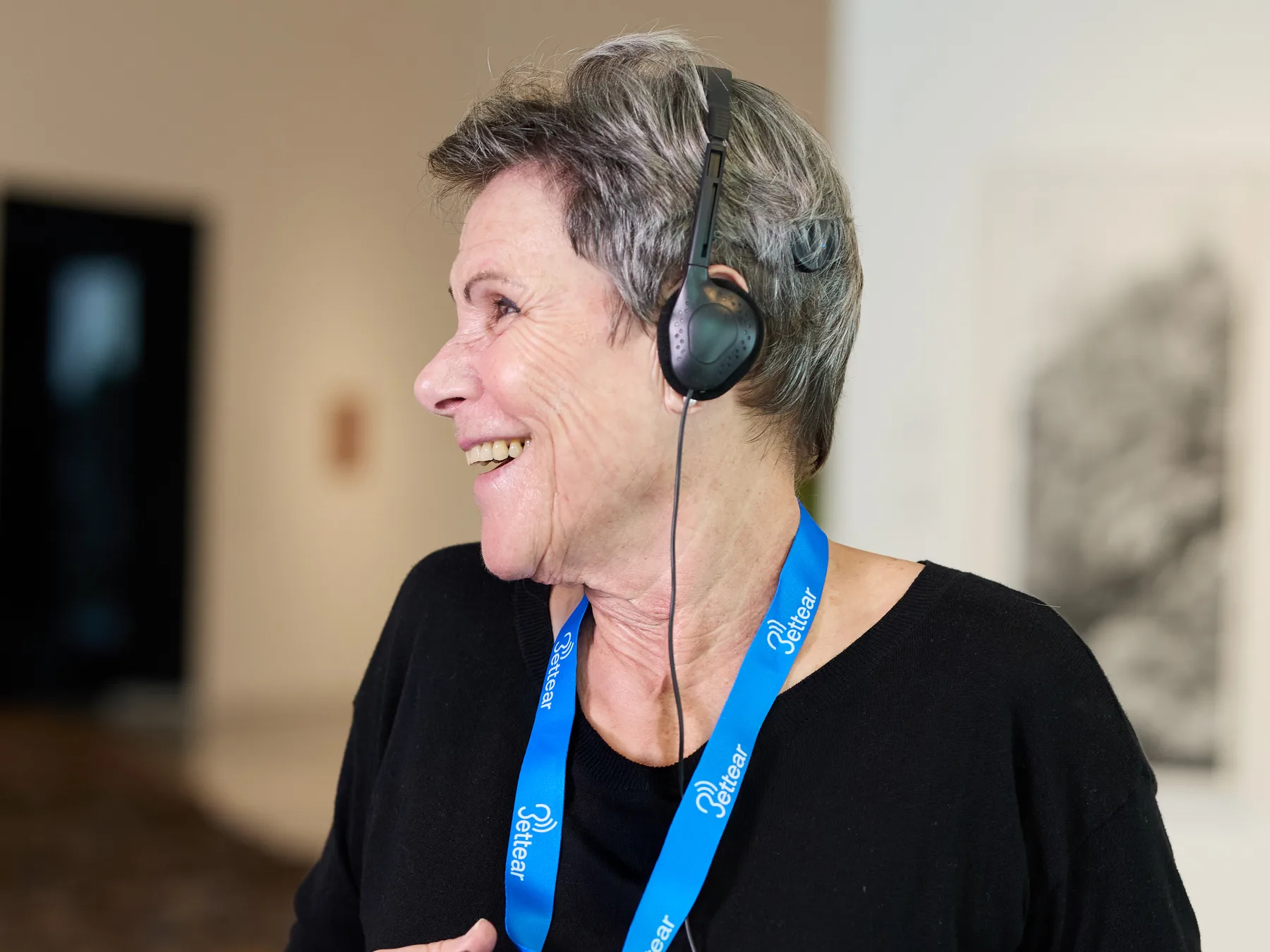 A visitor smiling as she listens on headphones connected to an RTX receiver
