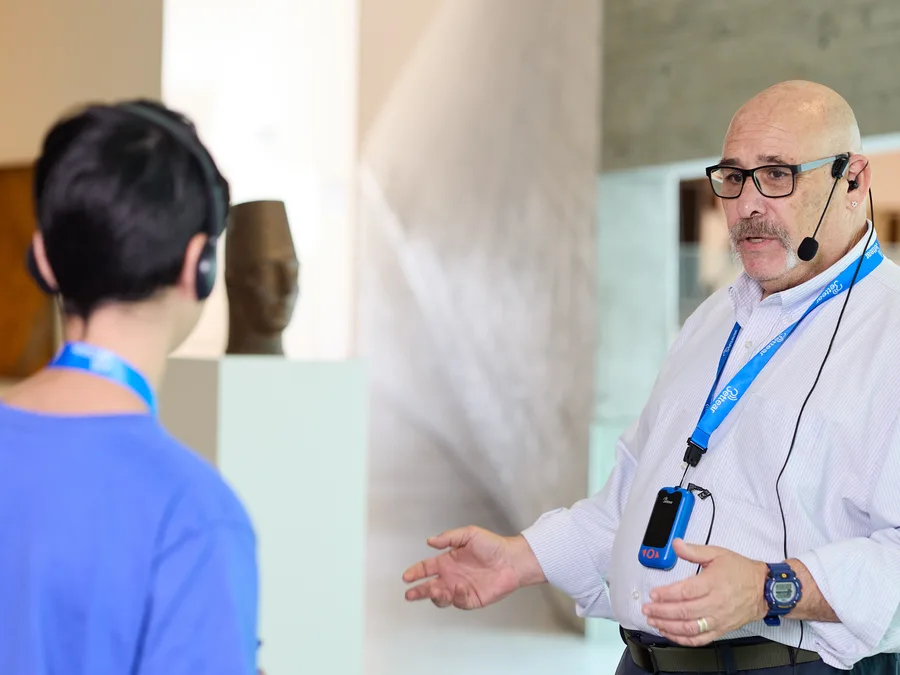 A museum guide speaking into a headset microphone to his group